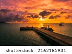 Wooden sea pier at sunset. Boat at sea pier at sunset. Orange sunset over sea pier. Pier boat at sunset sea
