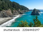 A sunny afternoon image of the beach and rocky cliffs that are south of the Arch Rock in the southern part of the Oregon Coast.