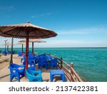 Beach cafe with plastic furniture, tables, chairs, wooden parasols in resort city. Clear sunny day. Beautiful outdoor fenced place on sea bank to eat and relax. Picturesque seascape, marine view