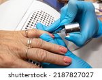 Small photo of The manicurist applies a topcoat with black dots to the finished hybrid nails with a brush.