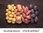 Heap of different types of potatoes on dark wooden rustic table