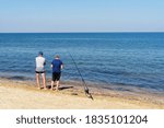 Small photo of Fishing on the seashore with a rod. From the shore, you can catch almost any fish that lives in the reservoir. The fishermen wait patiently for the fish to swallow the bait.