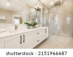 Small photo of Spacious master bathroom with glass wall shower free standing bathtub large mirrors toilet with privacy wall and white cabinets
