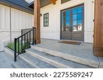 Small photo of classic home exterior with cement tile patio deck stone entry wide front door patio with chairs and a fire pit area with trees and bbq seating dining on a bright sunny colorful day blue sky
