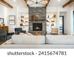 Small photo of Interior living room with fireplace stone and wood mantle staircase wooden flooring decorated and staged large bright windows classic and modern decor