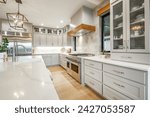 Small photo of Interior modern farmhouse kitchen and dining room with white countertops bar stools large dining table stainless appliances and view to living room with vaulted ceiling