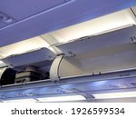 Opened locker over the seat row number 12 and 14 in cabin with luggage. Travel luggage with hat on locker in the economy class cabin in low cost airline airplane.