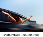 Journey of happy Asian woman with short hair hands up with blur motion from black car movement on blue sky background. Female travelers enjoy and smiling while looking at the view, on sunny days.