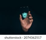Small photo of Security data technology and personal privacy on future phone concept. Shield with checkmark icon on the thin screen of futuristic transparent super slim glass smartphone in hand on dark background.