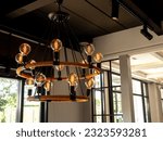 Modern chandelier in living room near glass window, loft style, vintage ceiling light or light bulbs hanging with from wooden ceiling, indoor, interior loft style building. Retro lighting decoration.