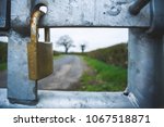 Closeup of a padlocked gate on the road to the countryside. No entry looking through to the countryside ahead. Where modern day meets mother nature
