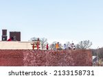 Small photo of GASTONIA, NC, USA-3 MARCH 2022: Four workers on a flat-roof commercial building. Construction, roofing, laborer