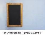 empty wooden chalk board on gray background. mock up of the black wooden frame on a wall, copy space for text