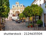 Small photo of Zahara de la Sierra, Spain - October 28 2021: The main street lined with orange trees, shops and cafes through the White Village of Zahara de la Sierra with the Chapel of San Juan de Letran in view.