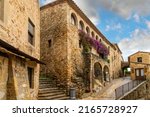 Small photo of Pals, Spain - June 1 2022: A small shop with purple bougainvillea bushes in the medieval walled village of Pals Spain, on the Costa Brava coast.