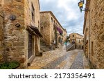 Small photo of Pals, Spain - May 25 2022: Souvneir shops alongside historic homes inside the medieval village of Pals, Spain after a summer rainstorm.