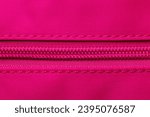 Small photo of Zip fastener background texture. A high-resolution close-up of a detail from a closed plastic zip fastening on a backpack made of an elastic pink nylon fabric. Macro photo.