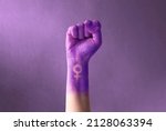 Raised purple fist of a woman...