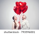 Valentine Couple. Portrait of Smiling Beauty Girl and her Handsome Boyfriend holding bunch of heart shaped air balloons and laughing. Happy Joyful Family. Love. Happy Valentine's Day