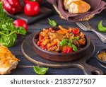 Small photo of Ajapsandali, cold vegetable stew or appetizer of eggplant, pepper, tomato and carrots in a clay bowl on a brown wooden background. eggplant recipes. Georgian cuisine