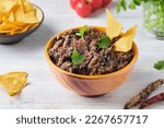 Small photo of Refried beans, a dish of black beans, fried onions and spices in a yellow ceramic bowl on a light wooden background. Bean dishes. Vegan, lenten food. Mexican cuisine.