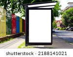 bus shelter at busstop. transit station. blank light billboard ad sign and lightbox. green urban street setting. soft background. safety glass design. white poster ad commercial poster space display.