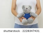 Close up pregnant woman holding teddy bear. Concept of pregnancy, Asian Young mother waiting of the baby.