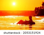 A man lies on an inflatable ring holding a phone in his hands at sunset. Relax after a day at work. The traveler enjoys nature, warm weather and beautiful sunsets.