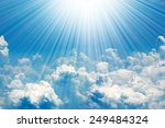 Sunrays in blue sky with white clouds