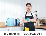 Portrait of Asian young cleaning service woman worker working in house. Beautiful girl housewife housekeeper cleaner crossing arm and smile, looking at camera after doing housework or chores at home.