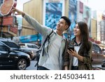 Asian attractive romantic couple travel in the city for honeymoon trip. New marriage man and woman backpacker tourist use mobile phone find destination, enjoy spend time on holiday vacation together.