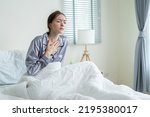 Caucasian beautiful sick girl in pajamas get up from sleep in bedroom. Attractive young woman feeling bad after waking up on bed and coughing in early morning at home. health care-lifestyles concept.
