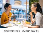 Small photo of Asian beautiful women having dinner with friend in restaurant together. Attractive young girl feeling happy and relax, having fun talking and eating food at their table in dining room in cafeteria.