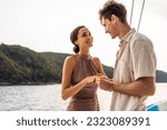 Caucasian young man make surprise proposal of marriage to girlfriend. Attractive romantic male proposing to beautiful happy woman with wedding ring enjoying surprise engagement while yachting together