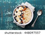 Bowl of oatmeal porridge with banana, blueberries, almonds, coconut and caramel sauce on teal rustic table, hot and healthy food for Breakfast, top view, flat lay