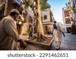 Small photo of Jeddah, Saudi Arabia - March 16th 2023: Scenic view of Arab men passing a tree in the courtyard of a traditional townhouse in the historic district Al Balad, Jeddah, KSA, Saudi Arabia