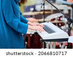 Small photo of Musician woman playing on white synthesizer keyboard piano keys, female hands on synthesizer, close up. Musician playing synthesizer on concert stage, professional playing on synth piano
