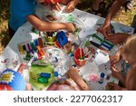 Small photo of Children paper crafting with parents in outdoor children party, painting, molding of plasticine and making figures cut from paper. Children hobby paper craft modeling, group development of children