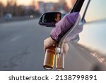 Small photo of concept of alcohol, dangerous driving. drink and drive. man drinks off a bottle of beer while driving car. driver throws the bottle out of the car window. drunk driving.
