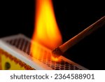 A matchstick lights after it is struck agains the flint surface of a match box. Everything is real, no flame filters