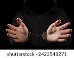 Small photo of Unknown, indistinguishable thug or hucker in handcuffs and black clothes is arested. Concept: Crime. isolated on black background