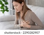 asian woman have chest pain caused by heart disease, leak, dilatation, enlarged coronary heart, press on the chest with a painful expression