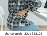 Small photo of woman holding her lower back while and suffer from unbearable pain health and problems, chronic back pain, backache in office syndrome, scoliosis, herniated disc, muscle inflammation