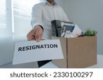 Stressful businessmen will resign from the company. He is lifting a brown paper box that holds personal items. resignation, job placement and vacancies concept.
