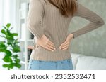 Asia beautiful woman holding her lower back while and suffer from unbearable pain health and problems, chronic back pain, backache in office syndrome, scoliosis, herniated disc, muscle inflammation