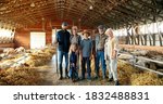 Small photo of Portrait of happy Caucasian family of three generations standing in shed with livestock and smiling. Old parents with children and grandchildren in stable. Farmers with kids at farm.