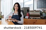 Small photo of Startup successful small business owner sme beauty girl stand with tablet smartphone in coffee shop restaurant. Portrait of asian tan woman barista cafe owner SME entrepreneur seller business concept