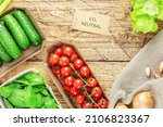 Vegan healthy food composition with local, farm vegetables in eco friendly packaging  with a label with the inscription carbon neutral on a wooden background. Fresh seasonal organic vegetables
