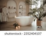 Small photo of Soft native hues organic shapes look of bathroom with big window oval bathtub in neutrals tones. Green palm plants candles bubblebath leasure and relaxation skin selfcare wellness luxury living