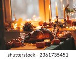 Small photo of Thanksgiving day dinner with holiday autumn decor and candles. Family dining room table set with delicious golden roasted turkey on platter garnished rosemary fresh small pumpkins